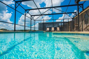 A swimming pool with a clear blue sky and clouds in the background, surrounded by a metal structure. - Sunrise Valley Villa by Orlando Short Term (Kissimmee)