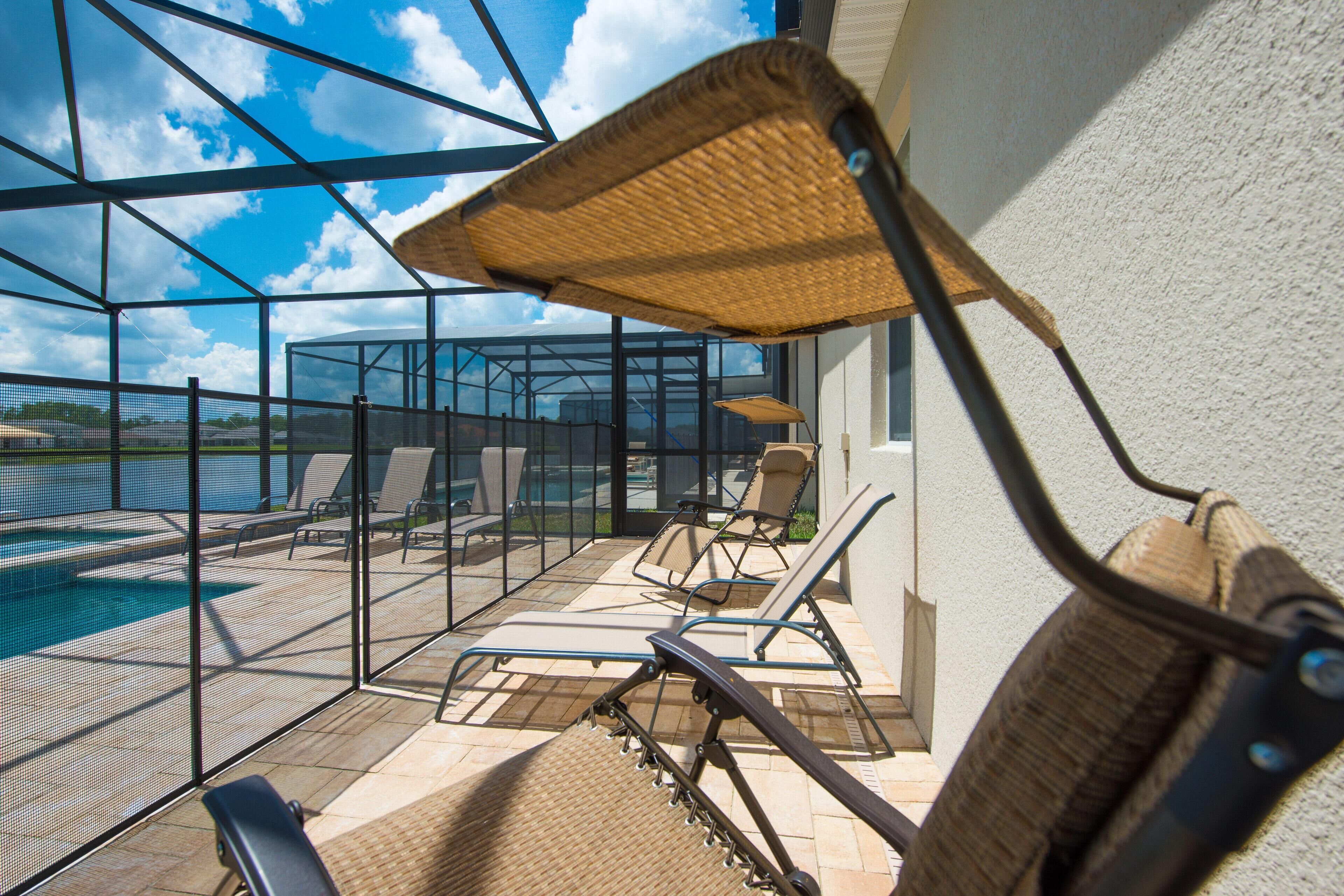 A sunlit outdoor area with a pool, lounge chairs, and a covered seating area.