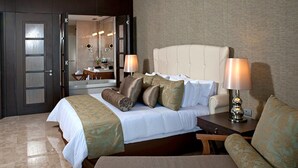 A hotel room with a bed, two bedside lamps, a chair, and a bathroom visible through an open door. - 5 star Diamond Private Residence Club (Marina Vallarta)