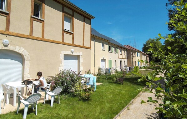 A row of single-story buildings with a garden area in front.