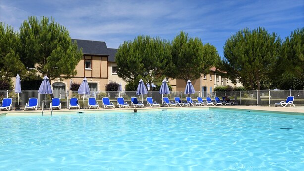A swimming pool with blue lounge chairs and umbrellas, surrounded by trees and a building. - Maisonnette Abordable 5mn de Lascaux (Montignac)