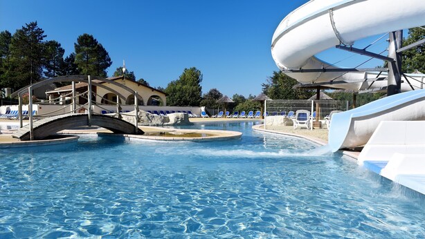 A swimming pool with a bridge, lounge chairs, and a water slide. - Appart Abordable avec Accès à 2 Piscines! (Salavas)