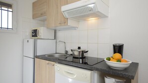 A modern kitchen with a dishwasher, microwave, stove, and a bowl of fruit on the counter. - Appart Abordable avec Accès à 2 Piscines! (Salavas)
