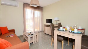 Una habitación de hotel con cama, escritorio con computadora, mesa de comedor con sillas y televisor.