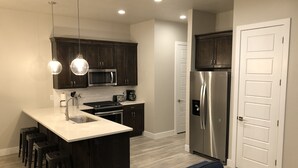 Una cocina moderna con armarios de madera oscura, un refrigerador de acero inoxidable y una encimera blanca.