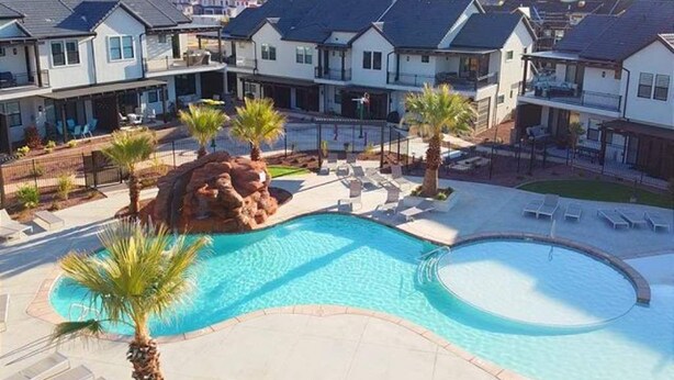Zona residencial con casas modernas, piscina y formación rocosa.