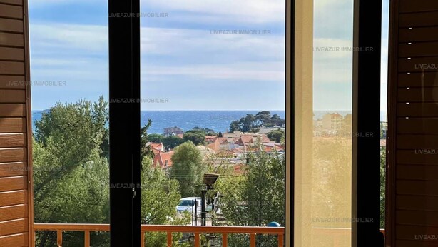 A balcony with a view of a coastal town, a lamp post, and a railing.