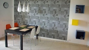 A dining area with a black table, white chairs, and a geometric patterned wall.