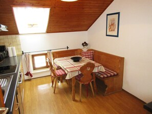 Une cuisine chaleureuse, avec des meubles en bois, une table à manger et une petite fenêtre.