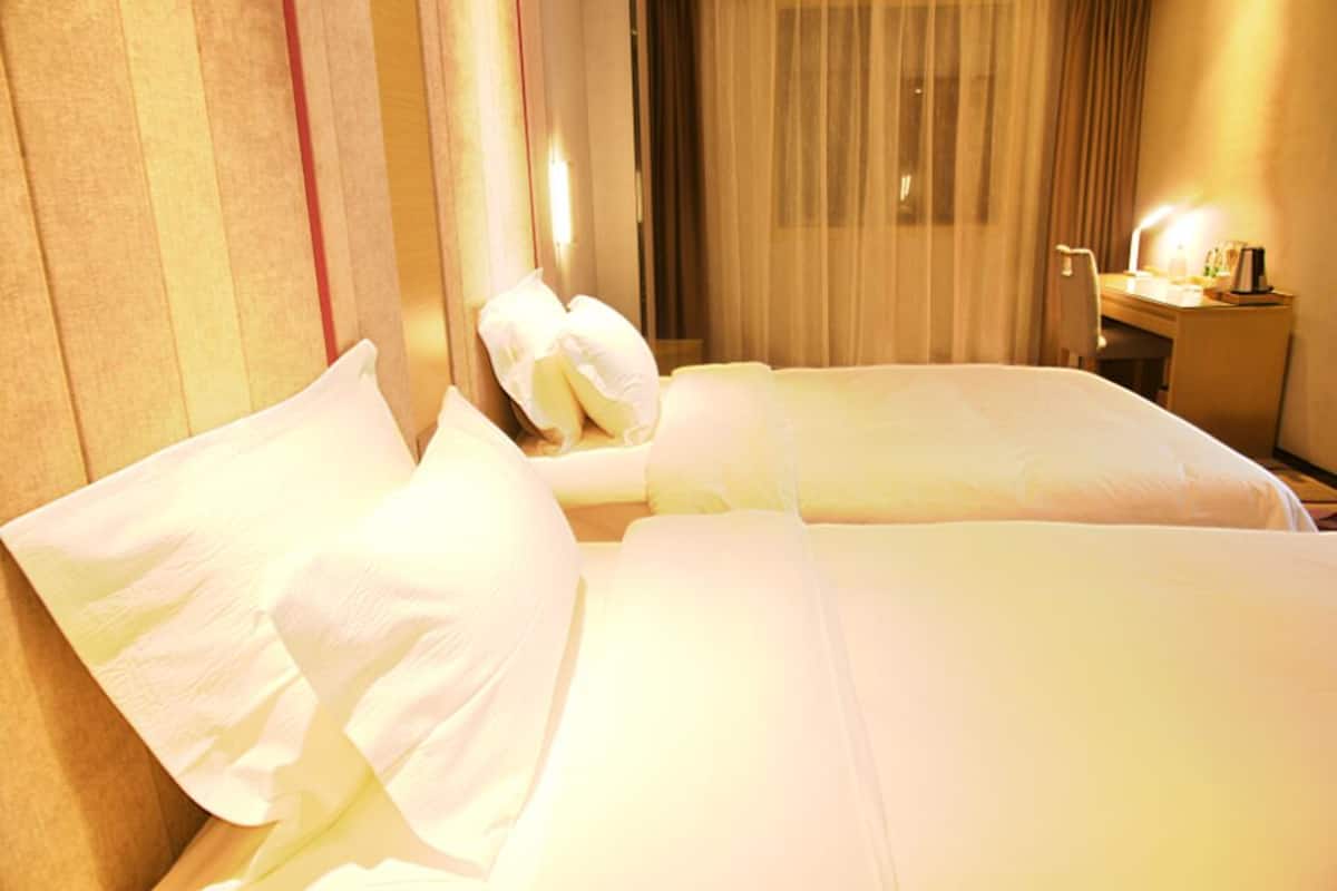 Quarto de hotel com duas camas, uma escrivaninha e uma cadeira.