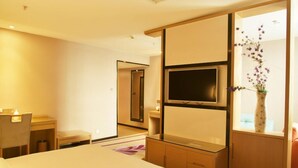 A hotel room with a bed, a desk, a TV, a mirror, and a vase with flowers. - Lavande Hotel Jingjiang Automobile Terminal (Taizhou)