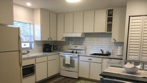 A modern kitchen with white cabinets, a built-in oven, a microwave, and a coffee maker. - Private Updated Mother In Law Apartment with Fenced Yard 4 miles from Siesta Key (Sarasota)