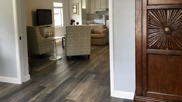 A spacious living area with a sofa, a patterned armchair, and a small table. A wooden cabinet with a decorative panel is visible on the right. - Private Updated Mother In Law Apartment with Fenced Yard 4 miles from Siesta Key (Sarasota)