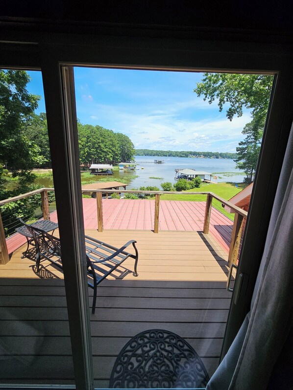 A deck with a view of a lake, surrounded by trees and a dock.