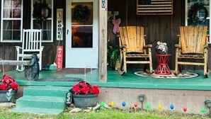 Un bâtiment rustique en bois, doté d’un porche, de deux chaises en bois, d’une petite table et d’une enseigne indiquant le numéro « 1130 ».