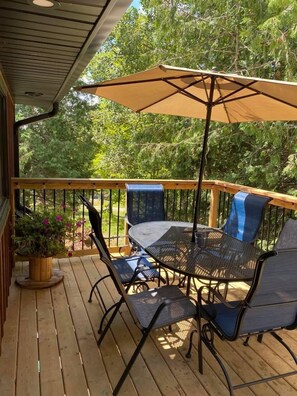 A wooden deck with outdoor furniture, including a table and chairs, and a large umbrella. - The Wright's Coach House  (Elora)