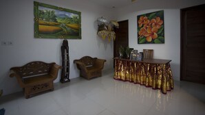 A room with two wooden sofas, a cabinet with a golden cloth, and a painting of flowers on the wall. - The Light Bali Villa (Seminyak)