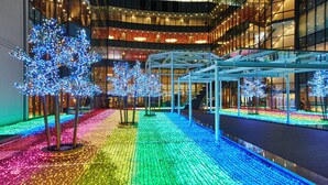 A modern building with a glass facade, a covered walkway, and illuminated trees. - Kobe Seishin Oriental Hotel (Kobe)