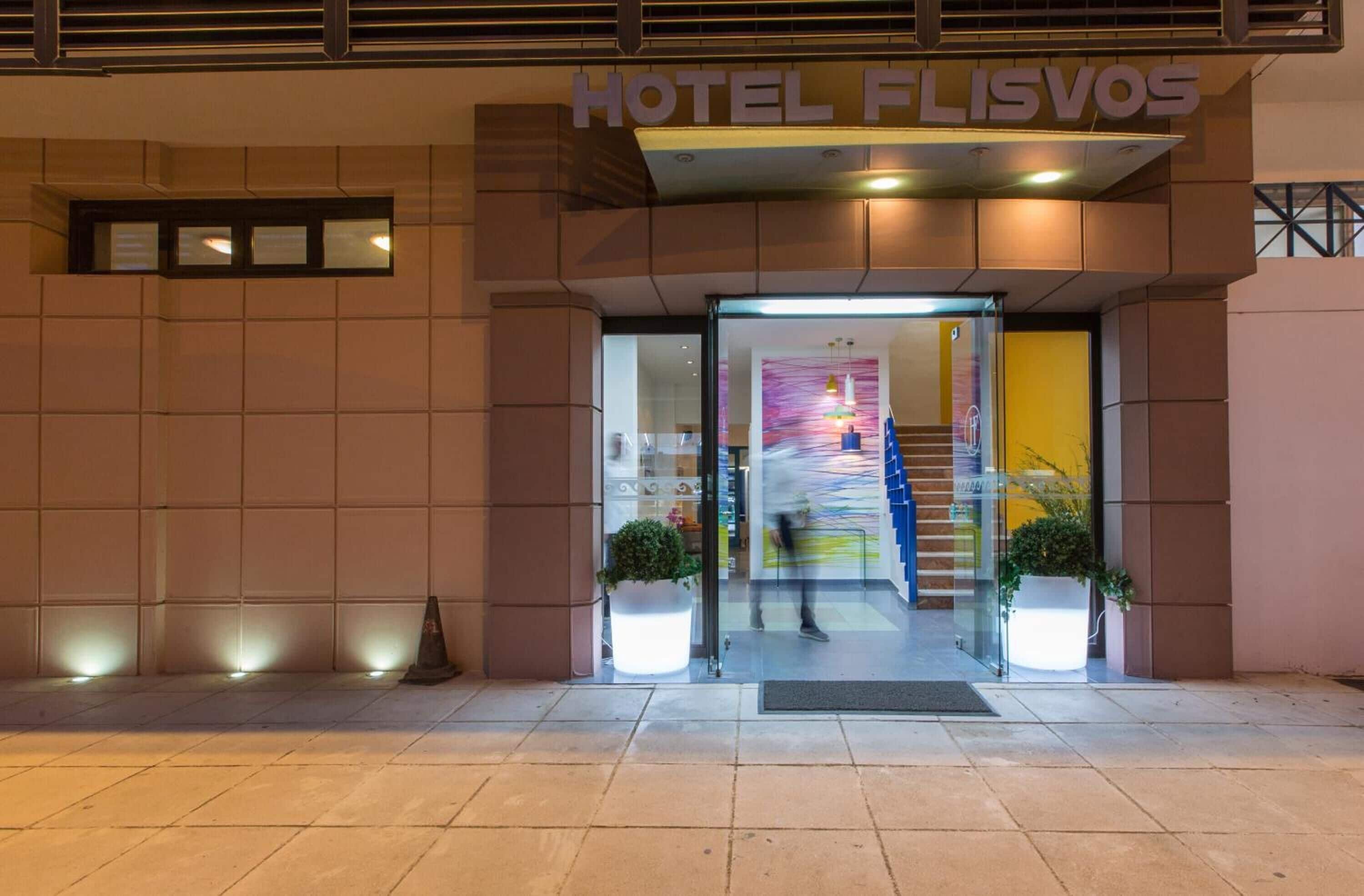 The entrance to Hotel Florvos with a modern design, featuring a glass door and a visible staircase leading inside.