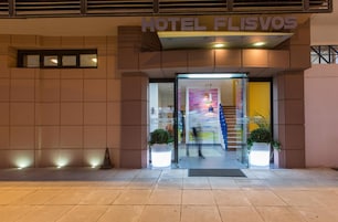 La entrada al Hotel Florvos con un diseño moderno, que incluye una puerta de vidrio y una escalera visible que conduce al interior.