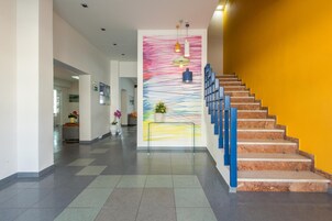 Un interior moderno con una escalera, un cuadro abstracto y colorido, y una zona de recepción.