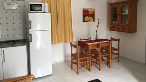 Eine kleine Küche mit Kühlschrank, Mikrowelle und Esstisch mit Stühlen.