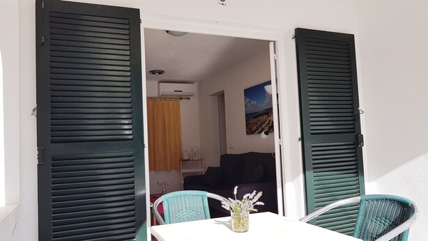 Ein Zimmer mit Tisch und Stühlen, einem Gemälde an der Wand und Blick ins Freie.