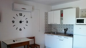 Eine kleine Küche mit weißen Schränken, einer Mikrowelle, einem Sp ülbecken und einer Wanduhr.