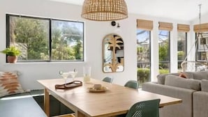 Un espace repas moderne avec une table en bois, des chaises et un luminaire suspendu.