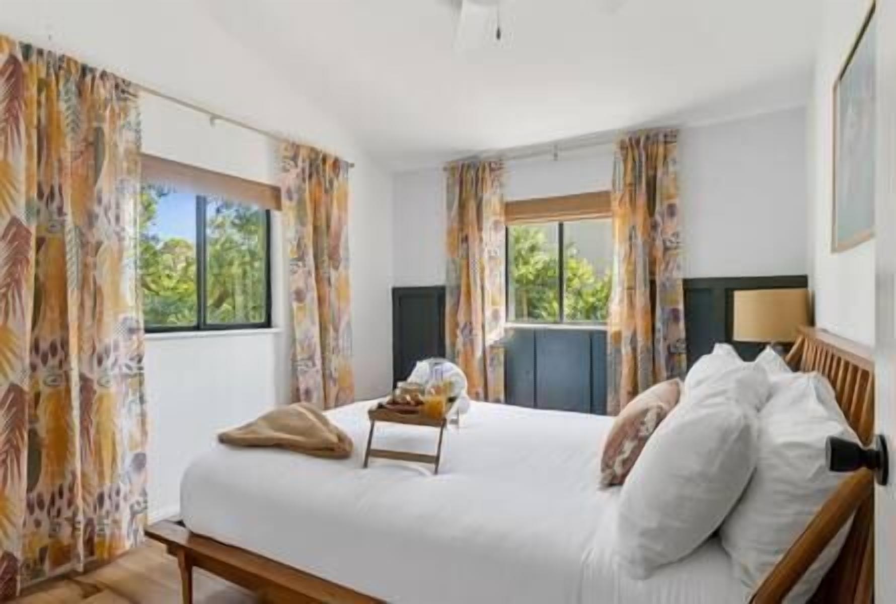 Une chambre d’hôtel avec un lit, des rideaux, une fenêtre et une lampe.