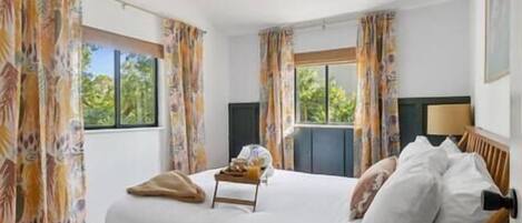 Une chambre d’hôtel avec un lit, des rideaux, une fenêtre et une lampe.