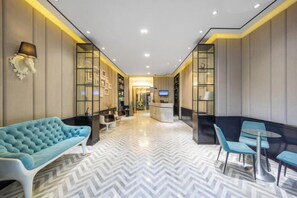 A hotel lobby with a herringbone floor pattern, a reception desk, seating areas, and a large blue sofa. - XiYuHotelle (Lingjiao Lake Wanda Plaza Store ) (Wuhan)