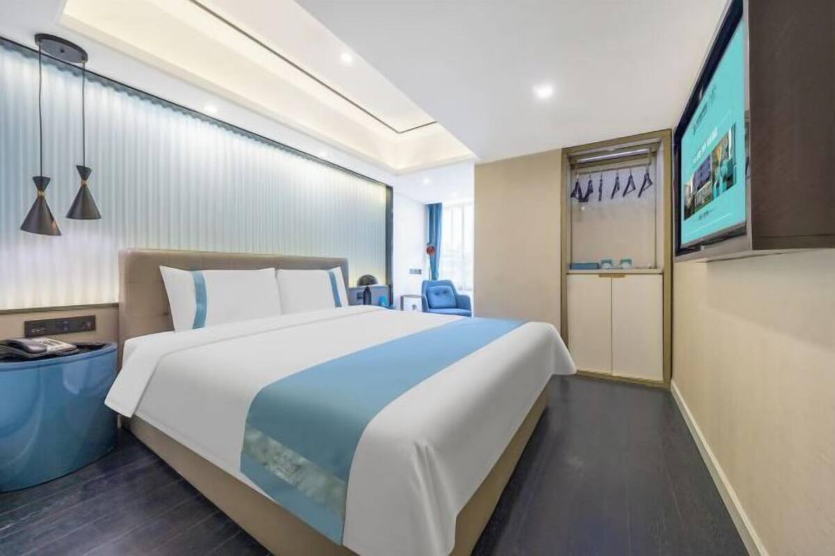Une chambre d’hôtel moderne avec un grand lit, des tables de chevet, une télévision et une armoire.