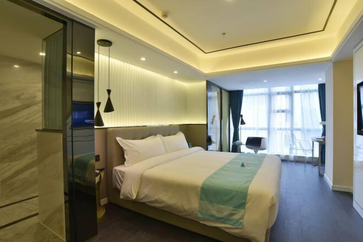 Une chambre d’hôtel moderne, dotée d’un grand lit, d’un bureau et d’une télévision.