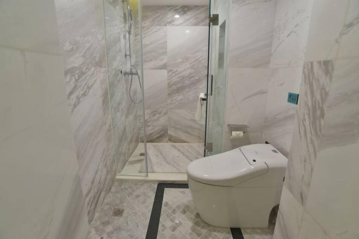 Une salle de bain moderne avec une douche à parois de verre, des toilettes et un sol en marbre.