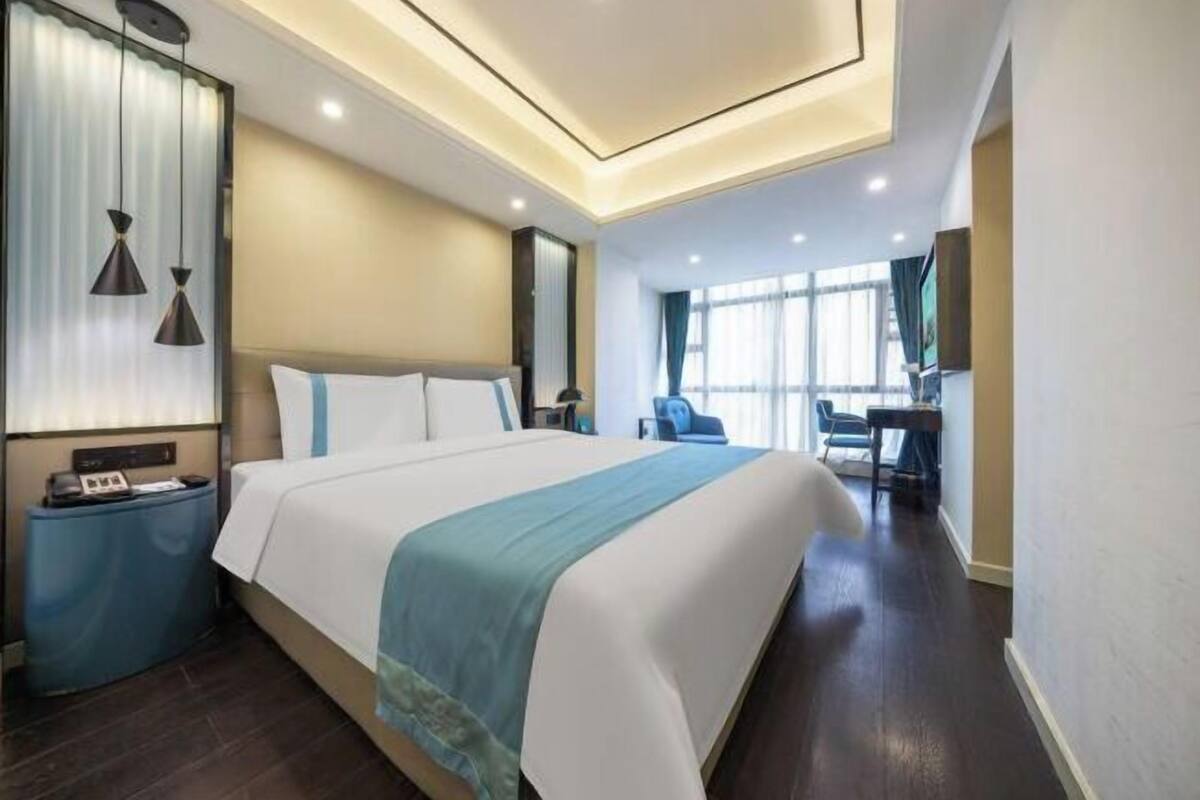 Une chambre d’hôtel avec un grand lit, des tables de chevet, un bureau et une chaise.