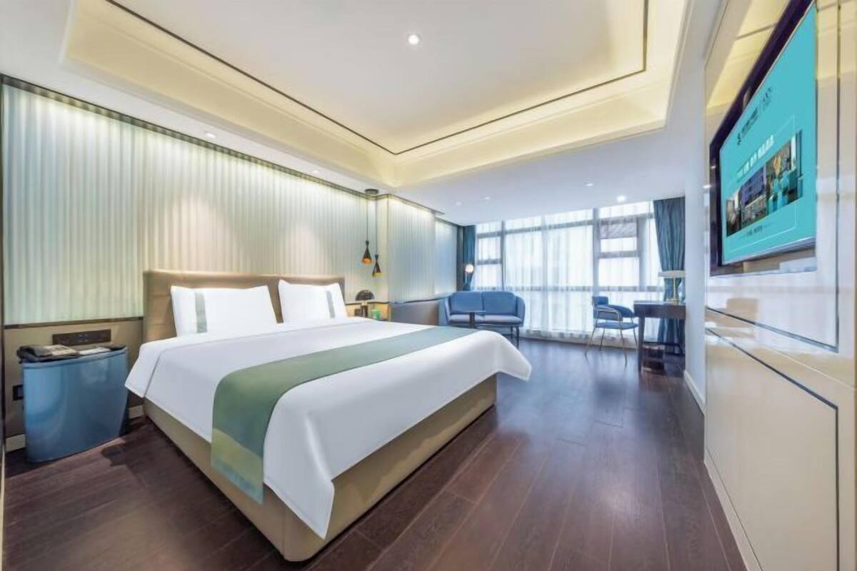 Une chambre d’hôtel avec un grand lit, un bureau, une chaise et un téléviseur.