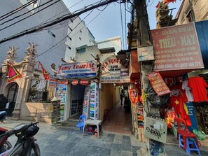A street view with various shops, including a 'Tony Tourist' sign, a 'Dien Vong' sign, and a 'Cua Hang Minh Lai' sign.