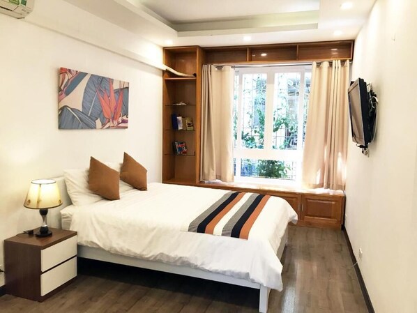 A bedroom with a bed, bedside table, lamp, and a window with curtains.