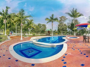 A pool area with multiple swimming pools, palm trees, and outdoor seating. - Finca Hotel San Isidro (Calarcá)