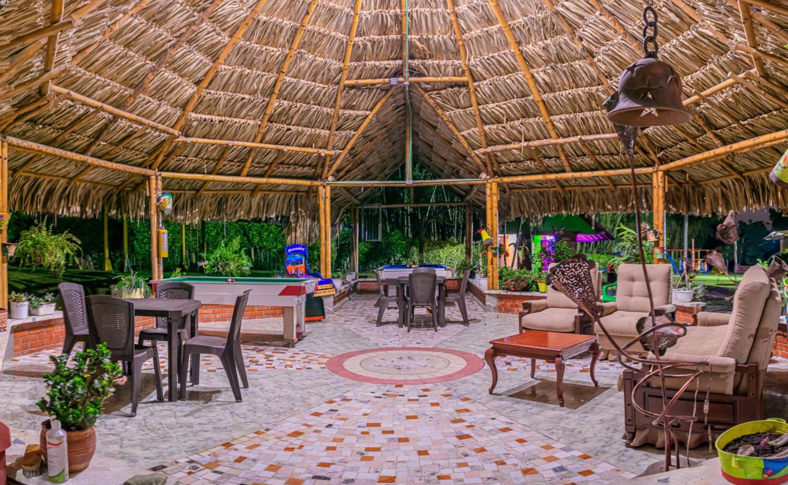 An outdoor area with a thatched roof, pool table, and seating arrangements.