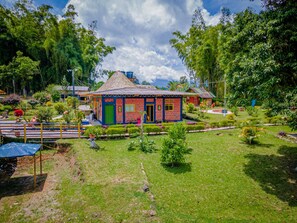 A colorful house with a thatched roof surrounded by a well-maintained garden. - Finca Hotel San Isidro (Calarcá)