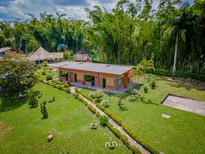 A modern building with a flat roof, surrounded by well-maintained lawns and trees. - Finca Hotel San Isidro (Calarcá)