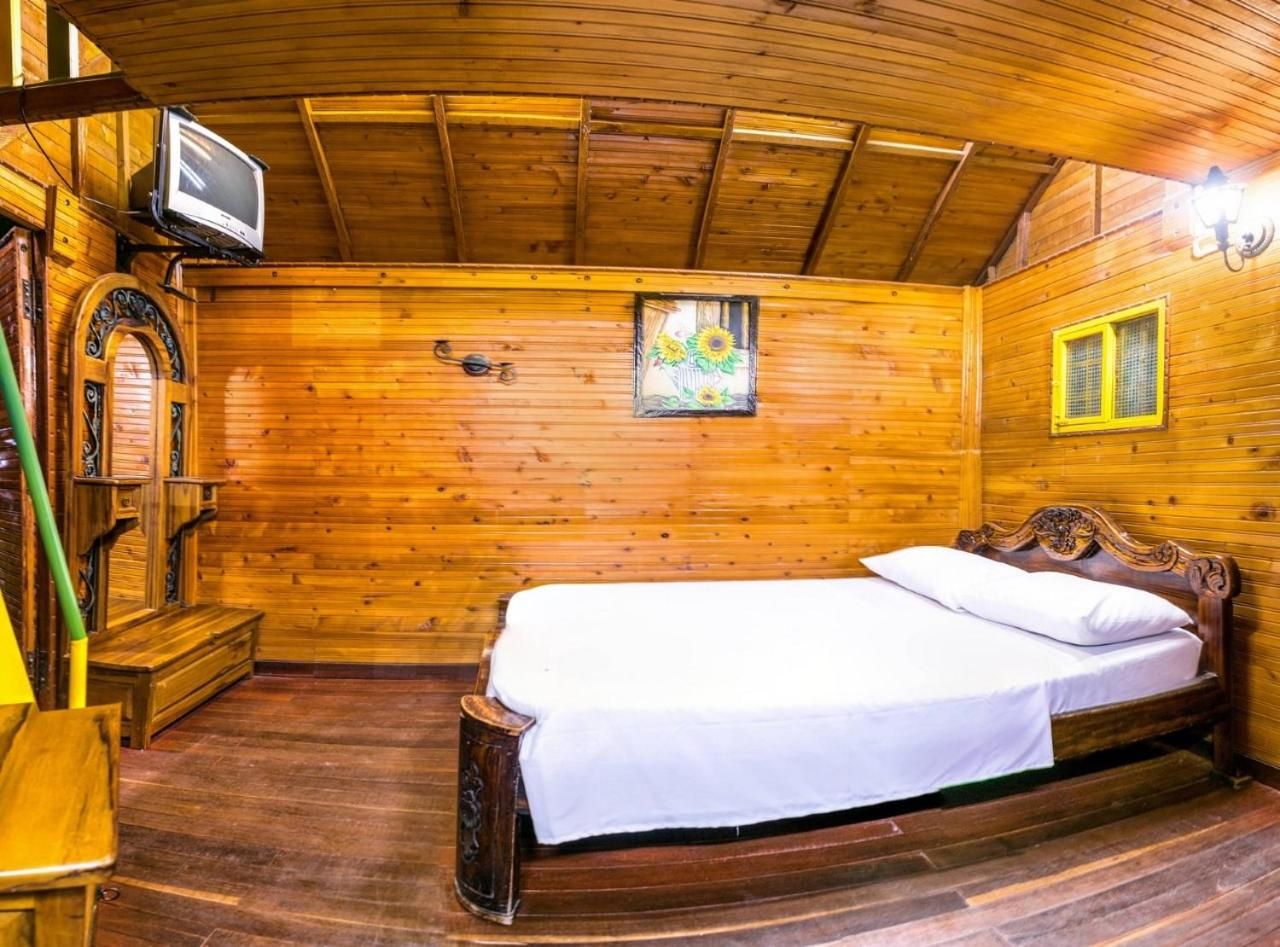 Una habitación de cabaña de madera con una cama, un televisor y una ventana con un cuadro de un girasol.