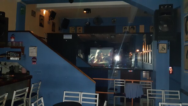 A bar area with a television screen, seating, and a staircase.
