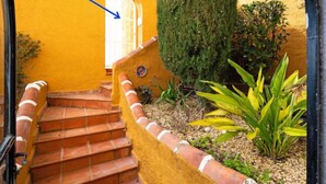 Eine Treppe führt zu einem Poolbereich mit einer gelben Wand und einem großen Baum.
