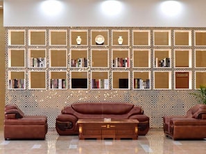 Ein Zimmer mit einem braunen Ledersofa, einem Holztisch und einer Wand mit mehreren Regalen, die mit Büchern und Dekoration gefüllt sind.