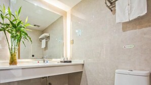 A modern bathroom with a white sink, mirror, and toilet. There is a plant on the counter and a towel rack on the wall. - Greentree Inn Tongxiang Chongfuzhen World Fur Cent (Jiaxing)