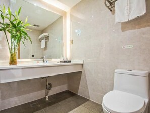 A modern bathroom with a white sink, mirror, and toilet. There is a plant on the counter and a towel rack on the wall. - Greentree Inn Tongxiang Chongfuzhen World Fur Cent (Jiaxing)
