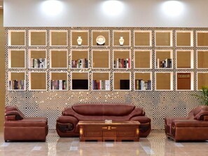 Un soggiorno con un divano in pelle marrone, un tavolino in legno e una parete decorata con mensole piene di libri e oggetti decorativi.